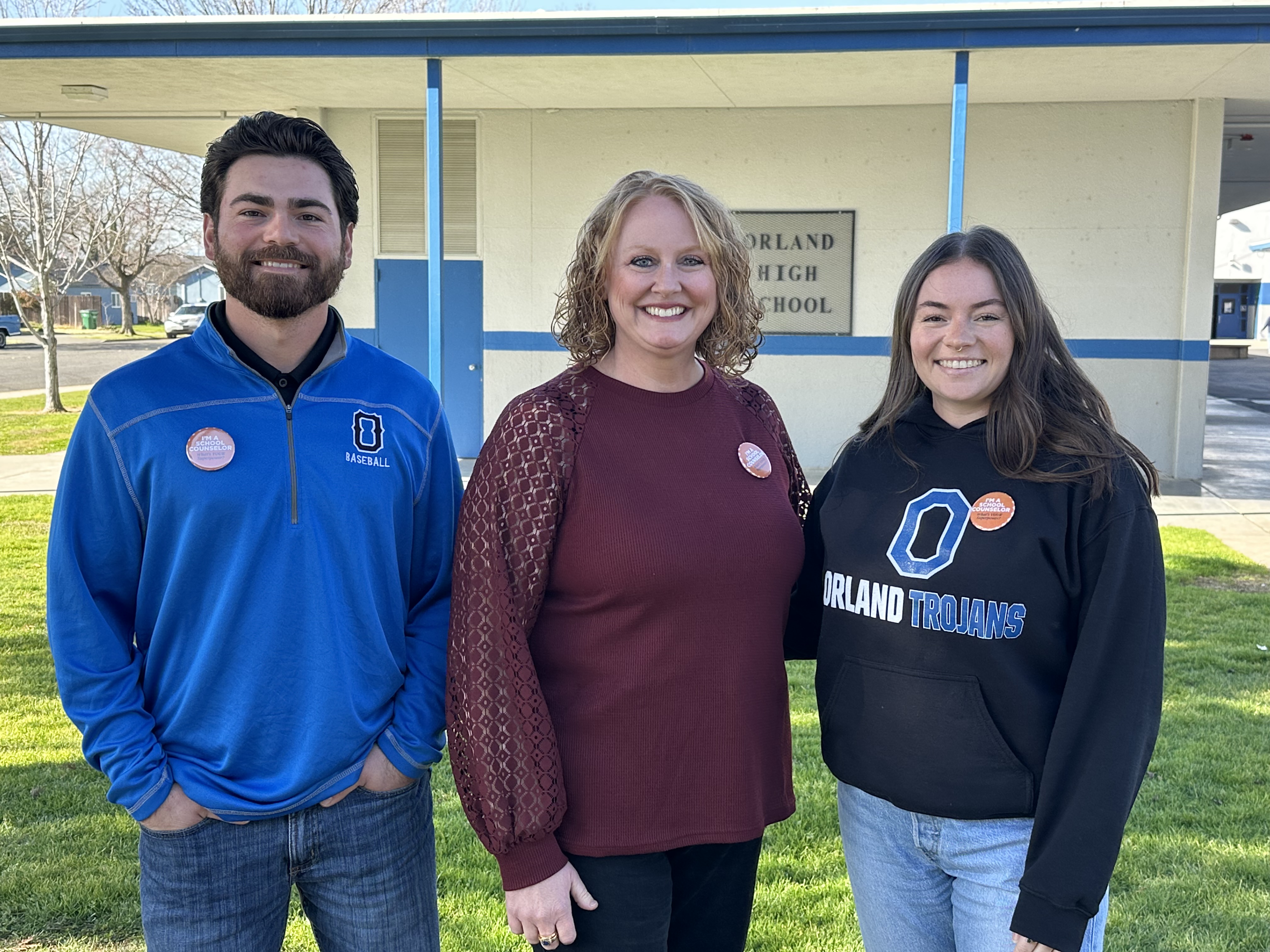 Male with beard and sweatshirt next to two females